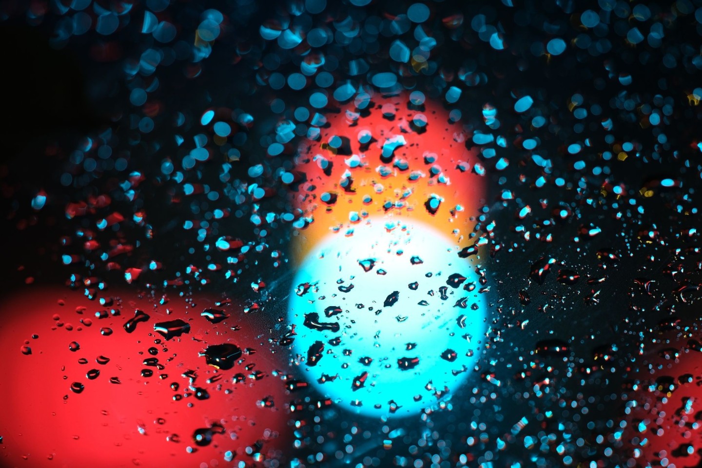 Eine Ampel hinter einer regennassen Scheibe eines Autos.