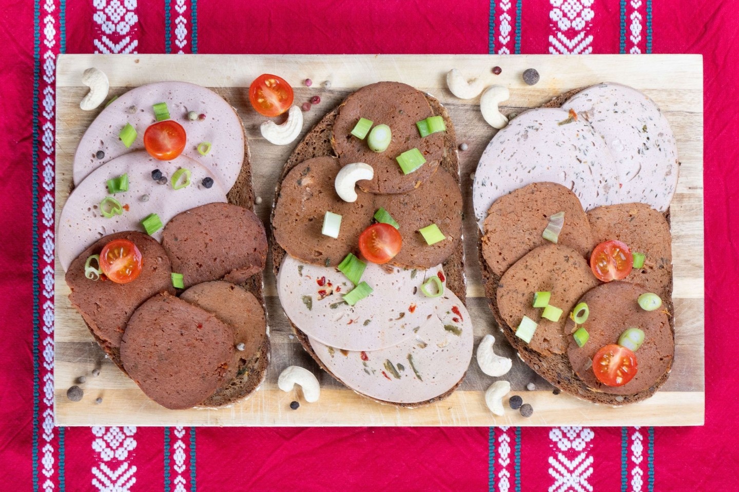 Brotscheiben belegt mit verschiedener veganer Wurst liegen auf einem Holzbrett (Symbolbild).