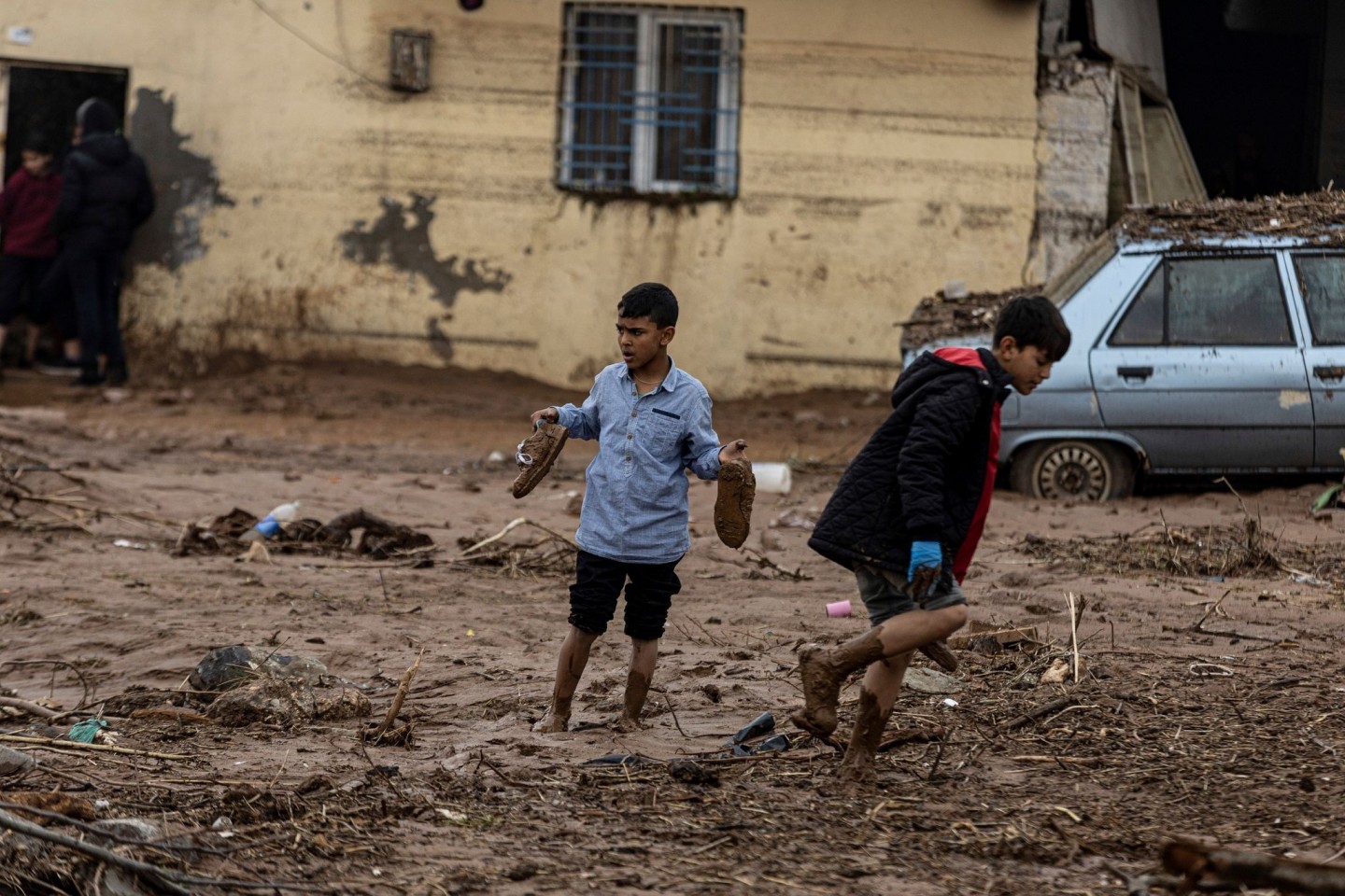 Kinder gehen nach heftigen Regenfällen eine schlammige Straße in Sanliurfa entlang.