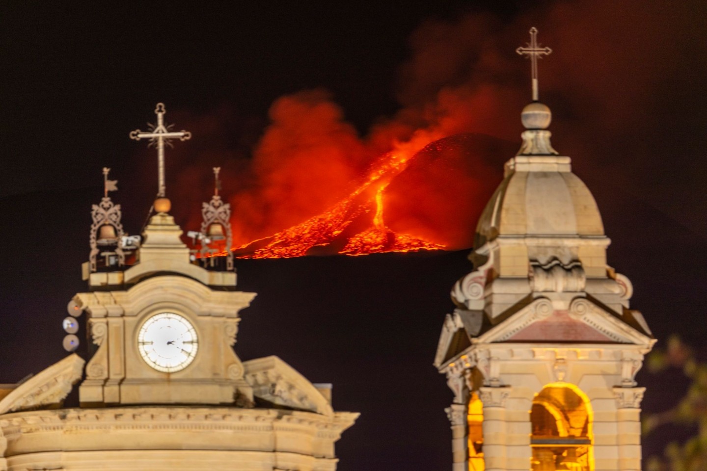 Hinter der Kirche Santa Maria della Guardia in Belpasso bei Catania bricht Lava aus einem Krater des Ätna.