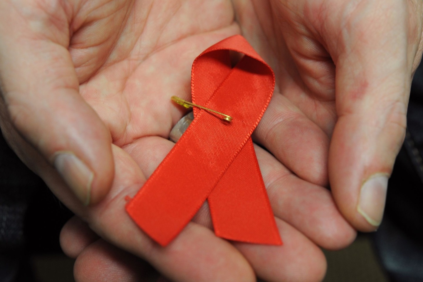 Ein mit dem HI-Virus infizierter Mann mit einer roten Schleife als Symbol der Solidarität mit HIV-Positiven und Aids-Kranken.