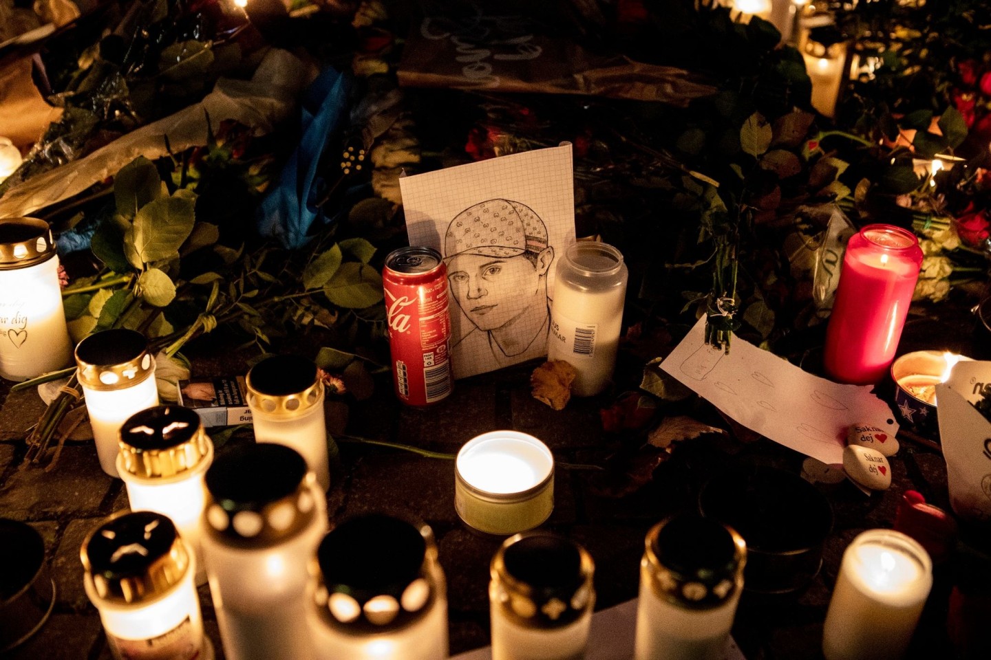 Ein gezeichnetes Porträt, Blumen und Kerzen liegen an einer provisorischen Gedenkstätte, wo der schwedische Rapper Einar 2021 erschossen wurde.