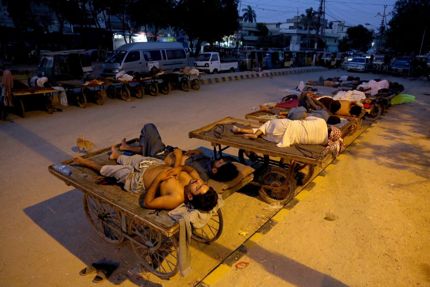 Verkäufer und Rikscha-Fahrer schlafen an einem heißen Sommermorgen in Karachi im Freien.