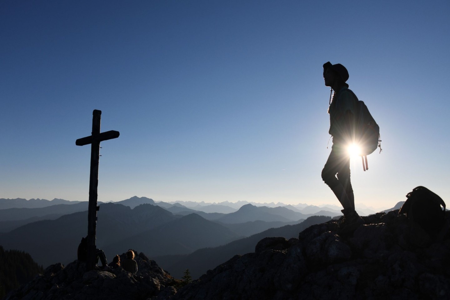 Eine Ausflüglerin genießt den Blick am Gipfelkreuz des Taubensteins.