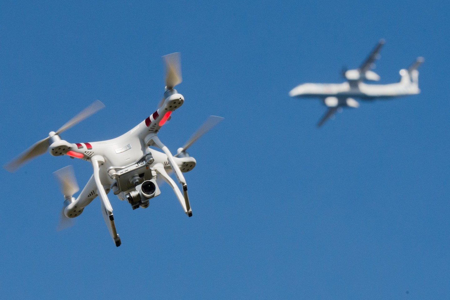 Eine private Drohne fliegt weit entfernt von einem Flugzeug.