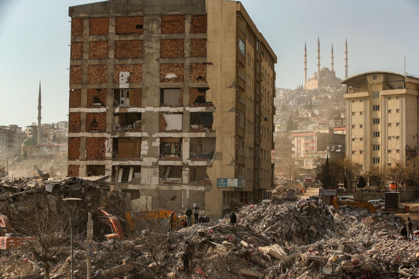 Menschen stehen im türkischen Kahramanmaras auf den Trümmern eines eingestürzten Gebäudes.
