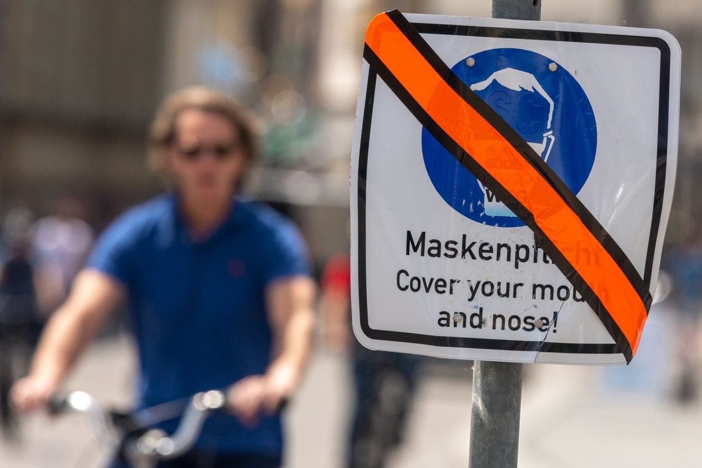 Ein mit orangen Klebeband durchgestrichenes Schild steht in der Münchner Innenstadt am Straßenrand. Die weitgehende Aufhebung der Maskenpflicht in Dänemark befeuert auch in Deutschland di...