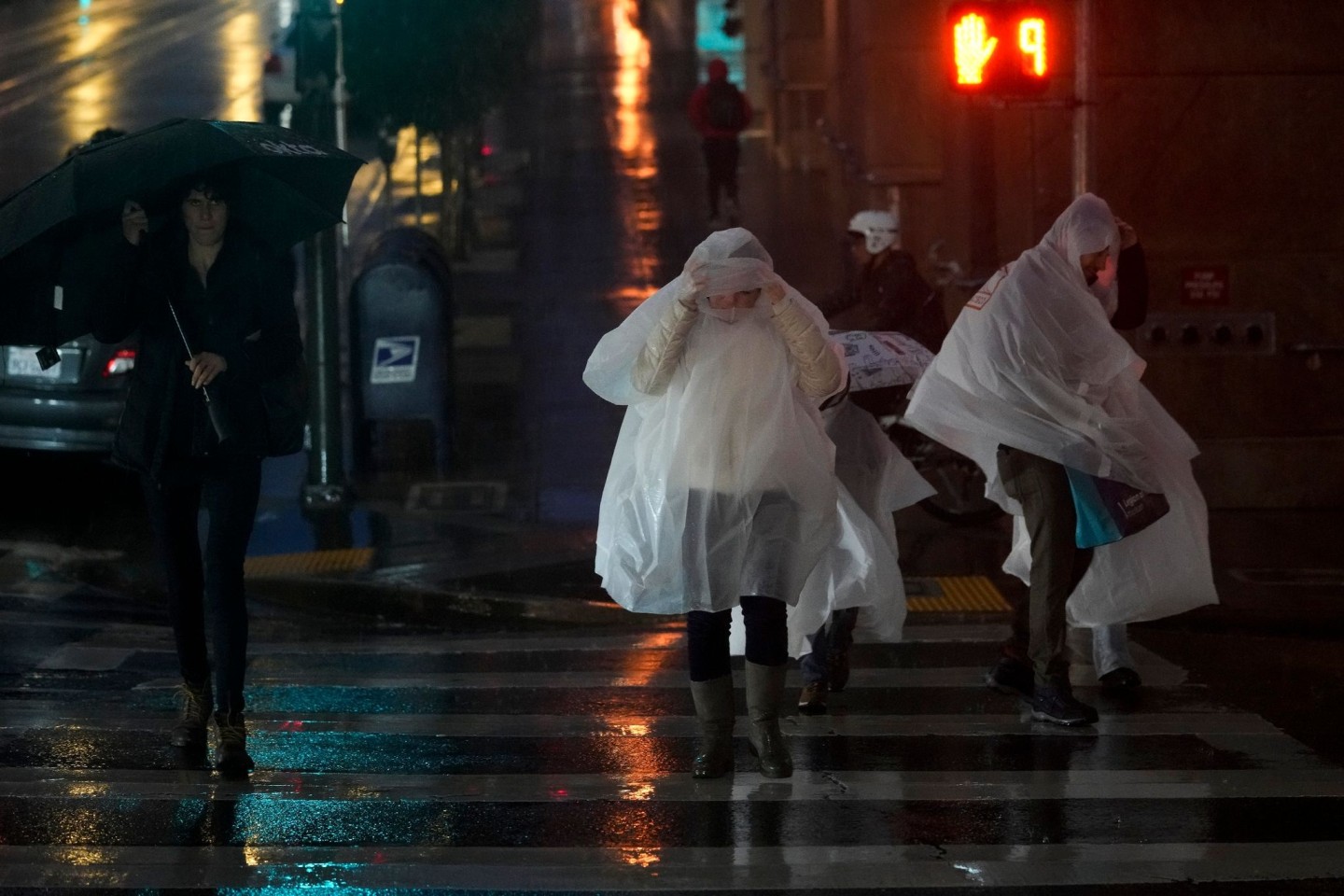 Menschen in Regenponchos überqueren eine Straße in San Francisco.