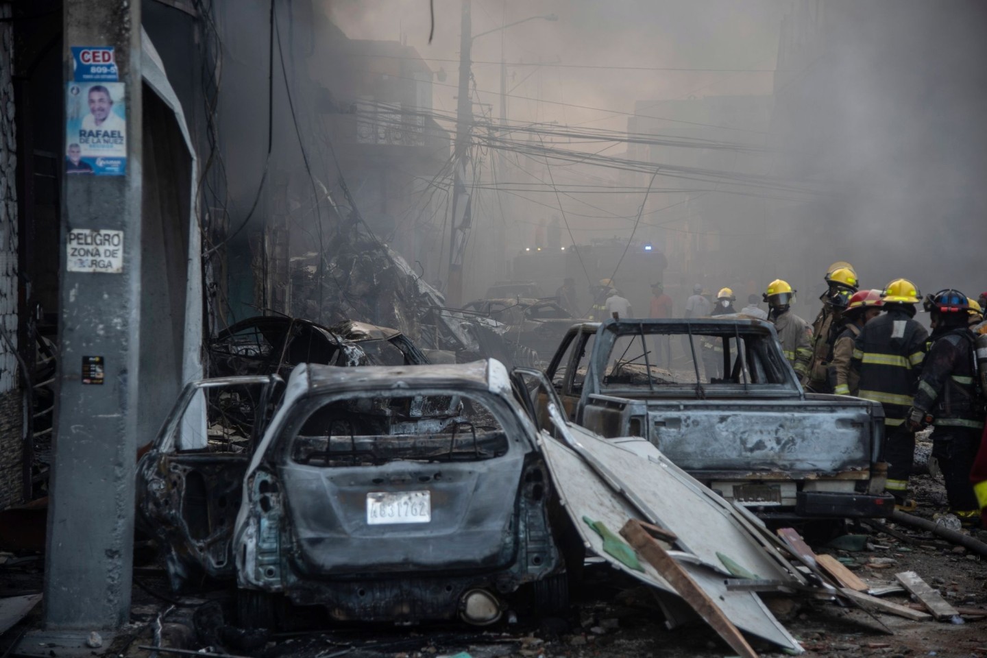 Feuerwehrleute arbeiten neben zerstörten Fahrzeugen nach einer starken Explosion, die ein Marktviertel mit vielen Geschäften erschüttert hat.
