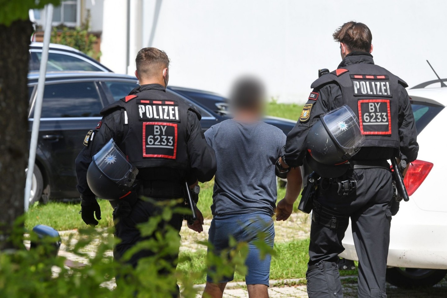Zwei Einsatzkräfte der Polizei führen in Miesbach einen Tatverdächtigen ab.