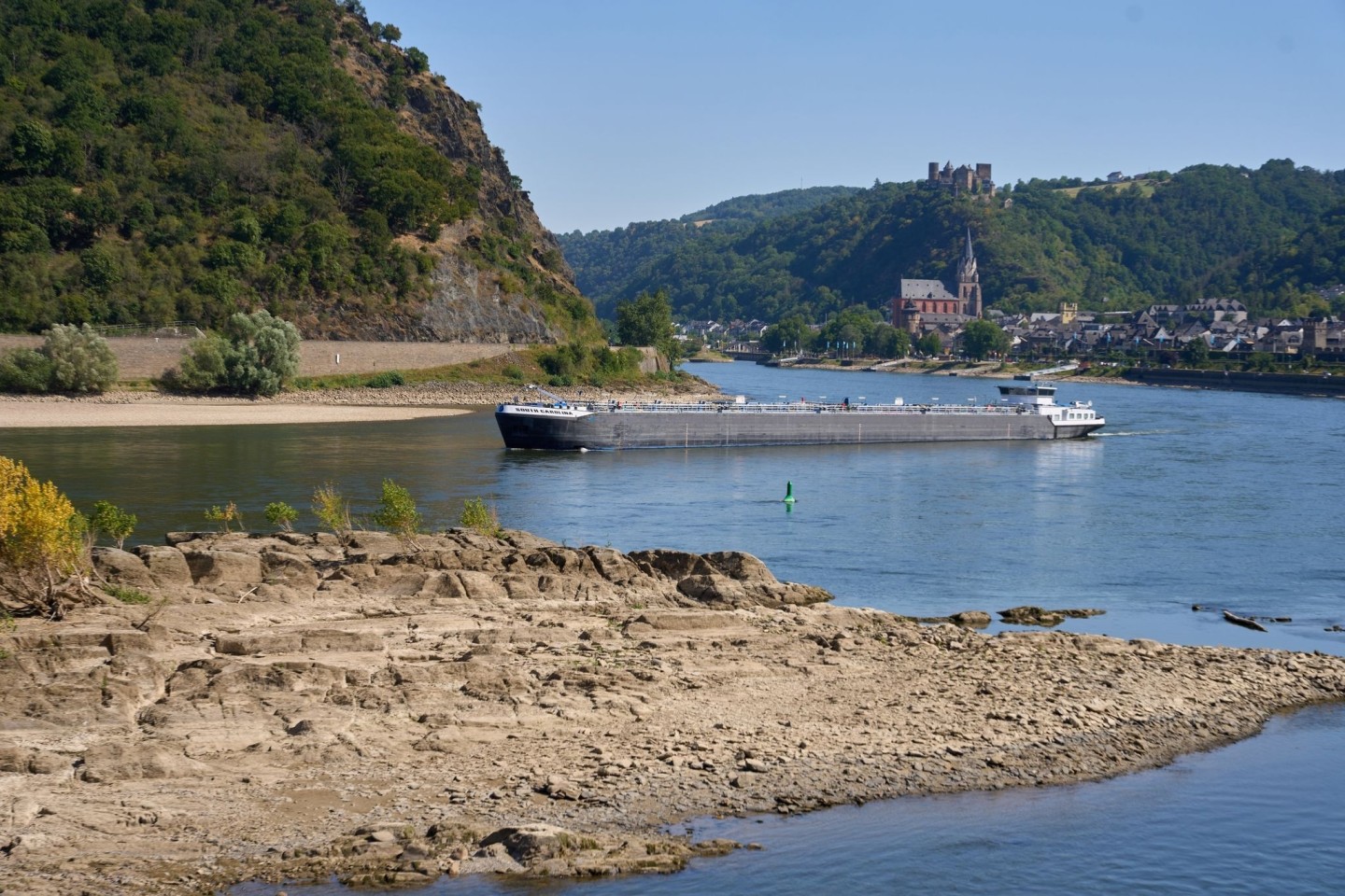 Ein Frachtschiff passiert auf dem Rhein einen Felsen. Durch die anhaltenden Trockenheit des Hochsommers fällt der Wasserspiegel des Mittelrheins immer weiter.