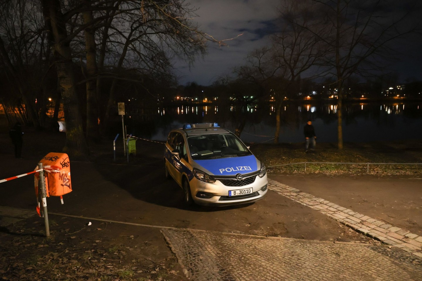 Ein Fahrzeug der Polizei steht am Ufer des Weißen Sees in Berlin-Pankow. In dem See sind zwei Leichen gefunden worden.