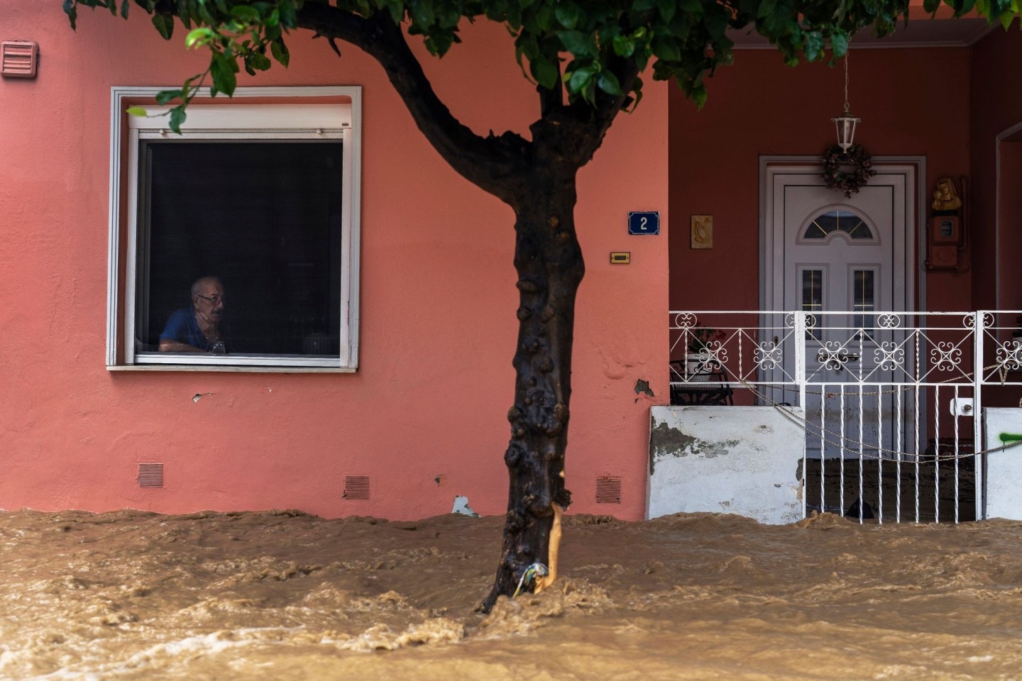 Ein Anwohner blickt aus dem Fenster seines Hauses auf die überschwemmte Straße.