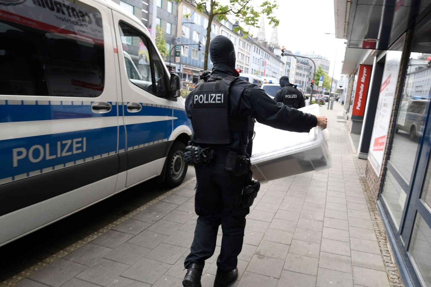 Ein Polizist trägt eine Kiste aus einem Gebäude, die die Polizei bei einer Razzia gegen Clankriminalität fand.