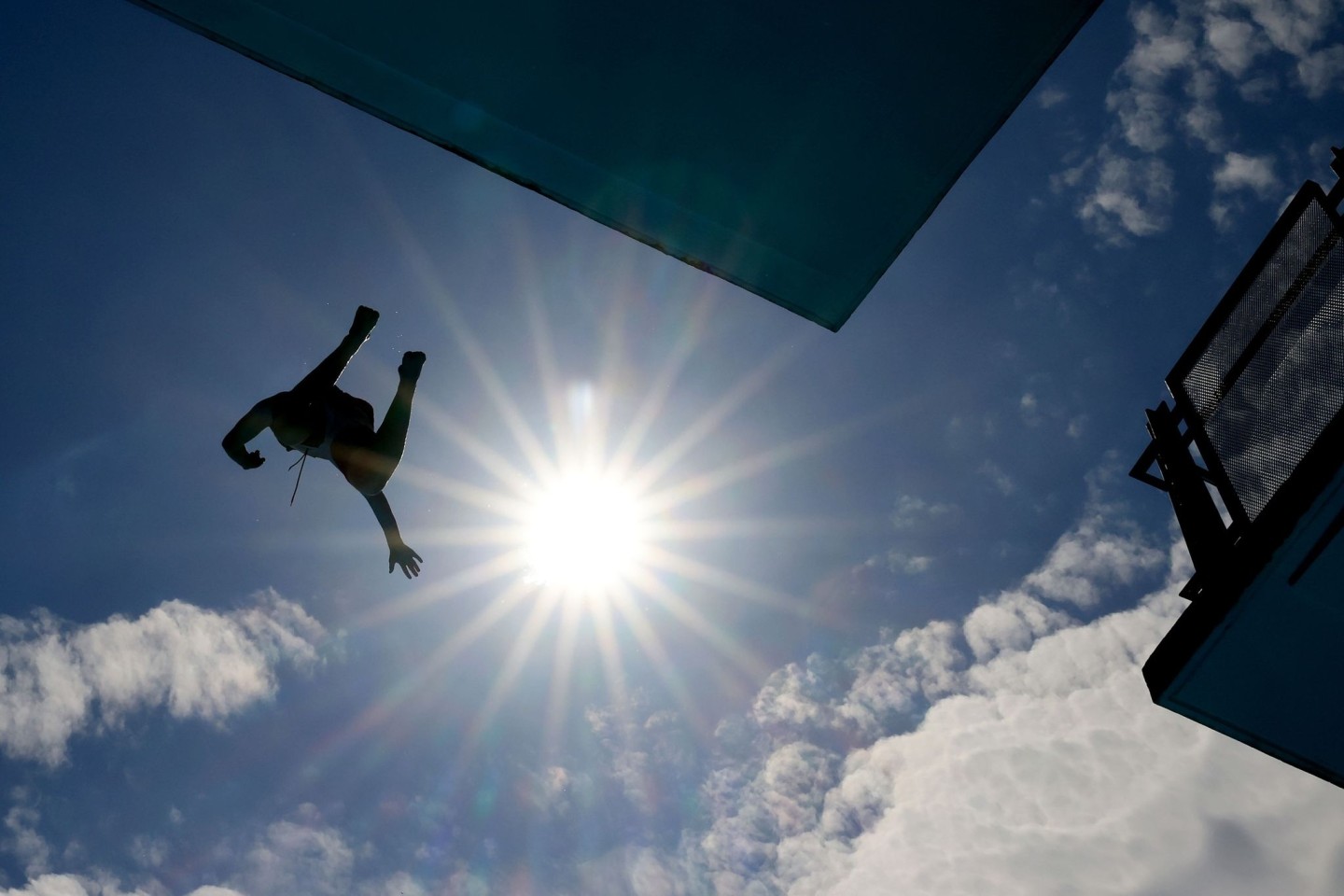 Ein Mann springt im Freibad vom Zehn-Meter-Turm.