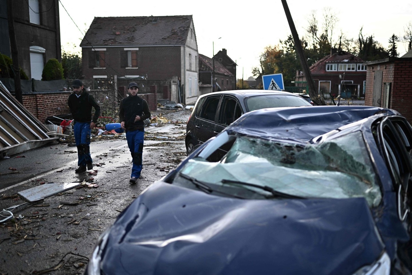 Anwohner gehen an einem beschädigten Haus und zerstörten Autos, nachdem ein Tornado die Region heimgesucht hat.