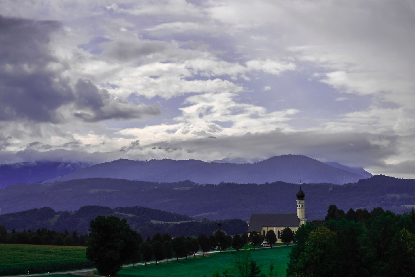 Wechselhaftes Wetter: Am Himmel über der bayerische Kirche von Wilparting in Irschenberg ziehen Wolken herüber.