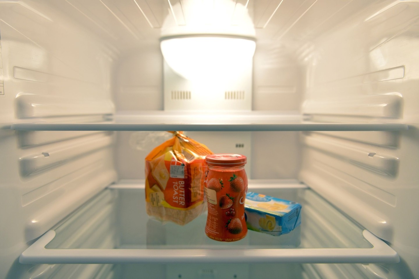 Konfitüre, Toastbrot und Butter stehen in einem Kühlschrank eines Einpersonenhaushalts.