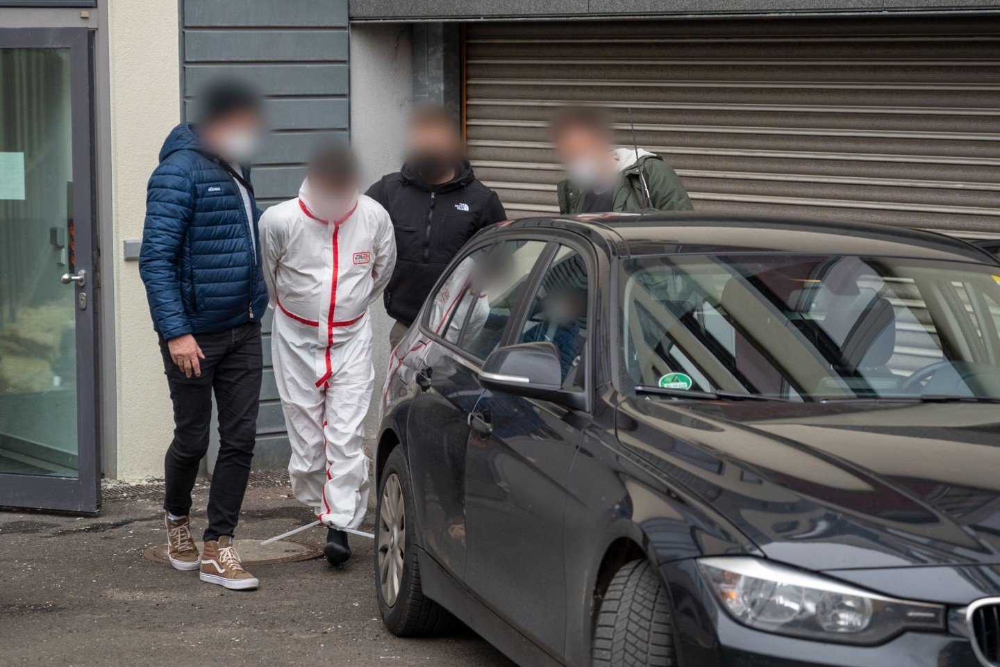 Polizisten bringen einen der Tatverdächtigen (im weißen Overall) nach dem Haftprüfungstermin am Landgericht Kaiserslautern aus dem Justizgebäude.