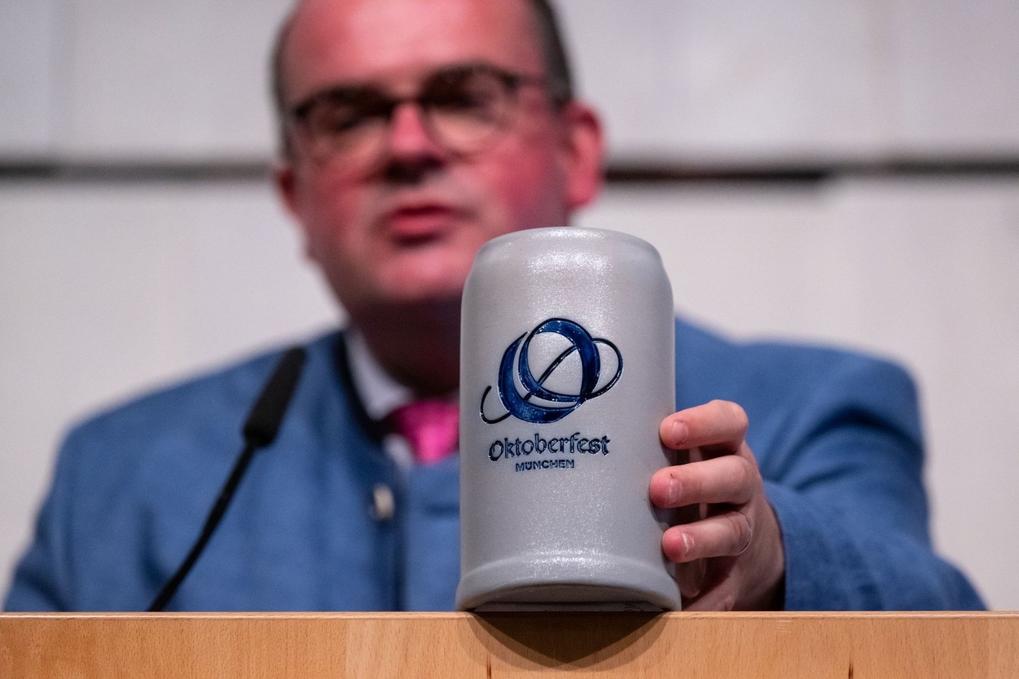 Clemens Baumgärtner (CSU), Referent für Wirtschaft und Arbeit der Landeshauptstadt München und Wiesn-Chef, zeigt das neue Logo des Oktoberfests auf einem Bierkrug.
