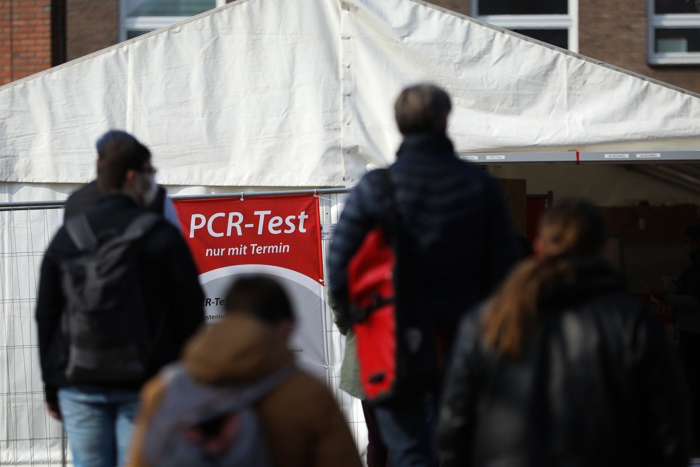 Menschen stehen für einen PCR-Test in einer Teststation am Lübecker Holstentor Schlange.