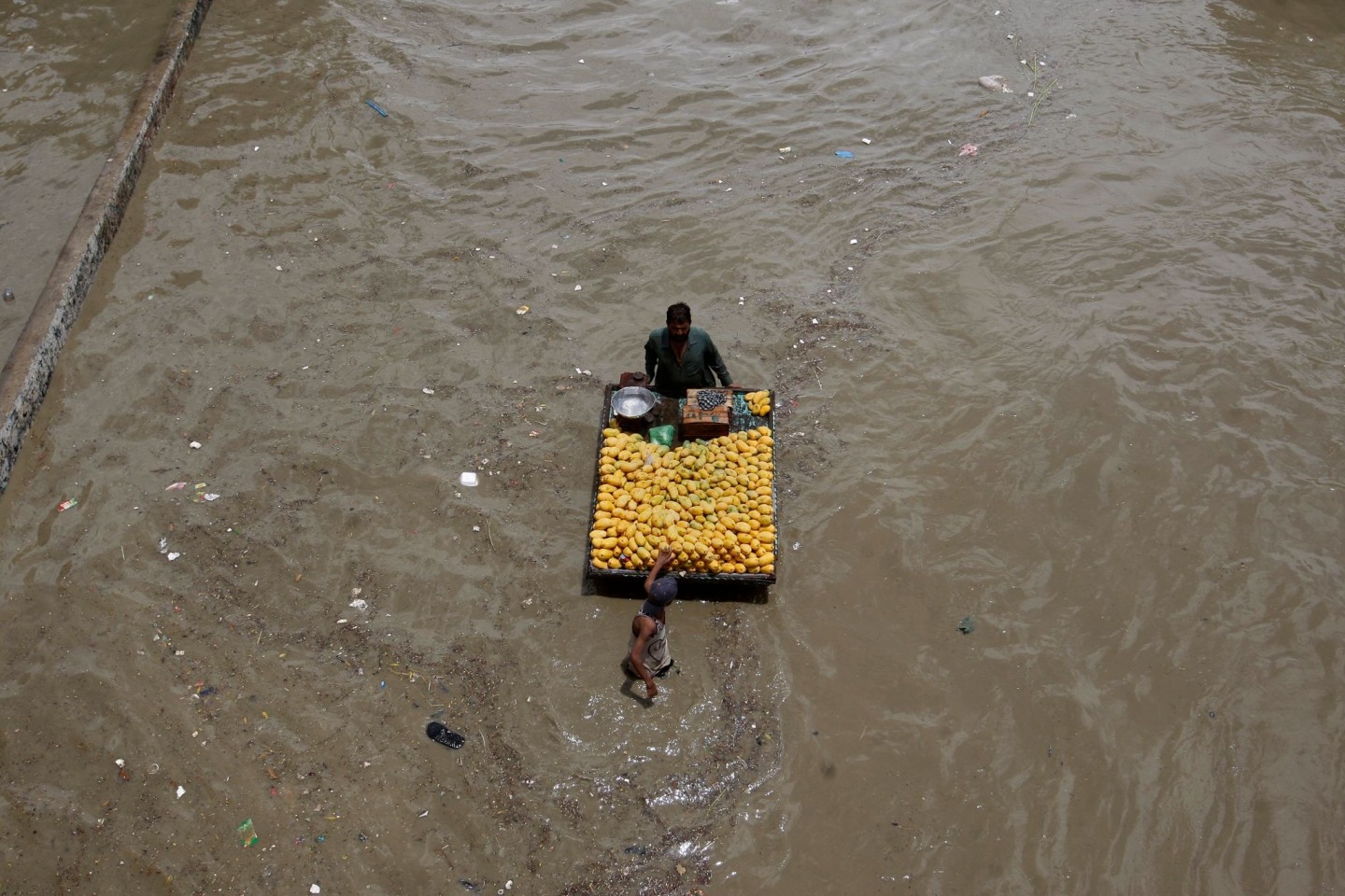 Ein Obstverkäufer geht nach heftigen Regenfällen durch eine überschwemmte Straße in Karachi.