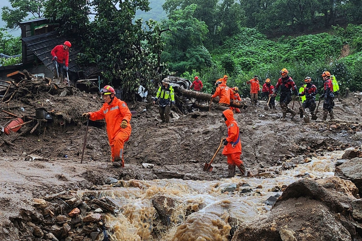 Rettungskräfte suchen nach Personen in Häusern, die nach durch starken Regen verursachten Erdrutsch eingestürzt sind.
