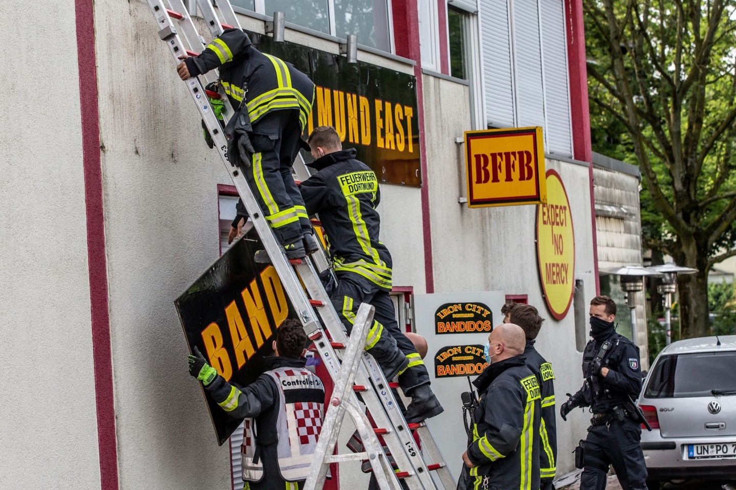 Feuerwehrleute entfernen unter Polizeischutz ein Schild am Vereinsheim der Rockergruppe «Bandidos».