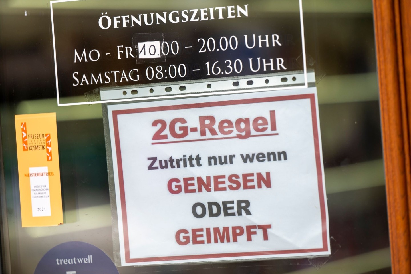 Ein Schild zur «2G-Regel» hängt an der Eingangstür eines Münchner Friseurladens.
