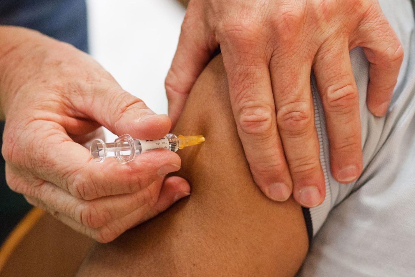 Ein Mann erhält eine Impfung gegen Grippe, Tetanus, Diphtherie, Keuchhusten (Pertussis) und Polio.