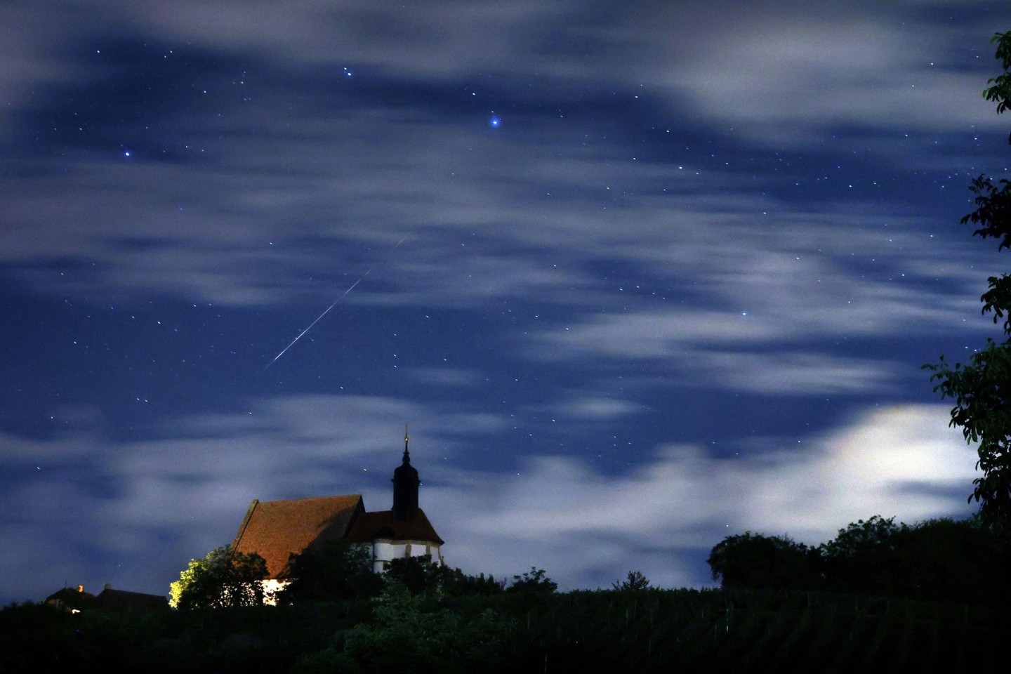 Eine Sternschnuppe verglüht am Himmel über der Wallfahrtskirche Maria im Weingarten.