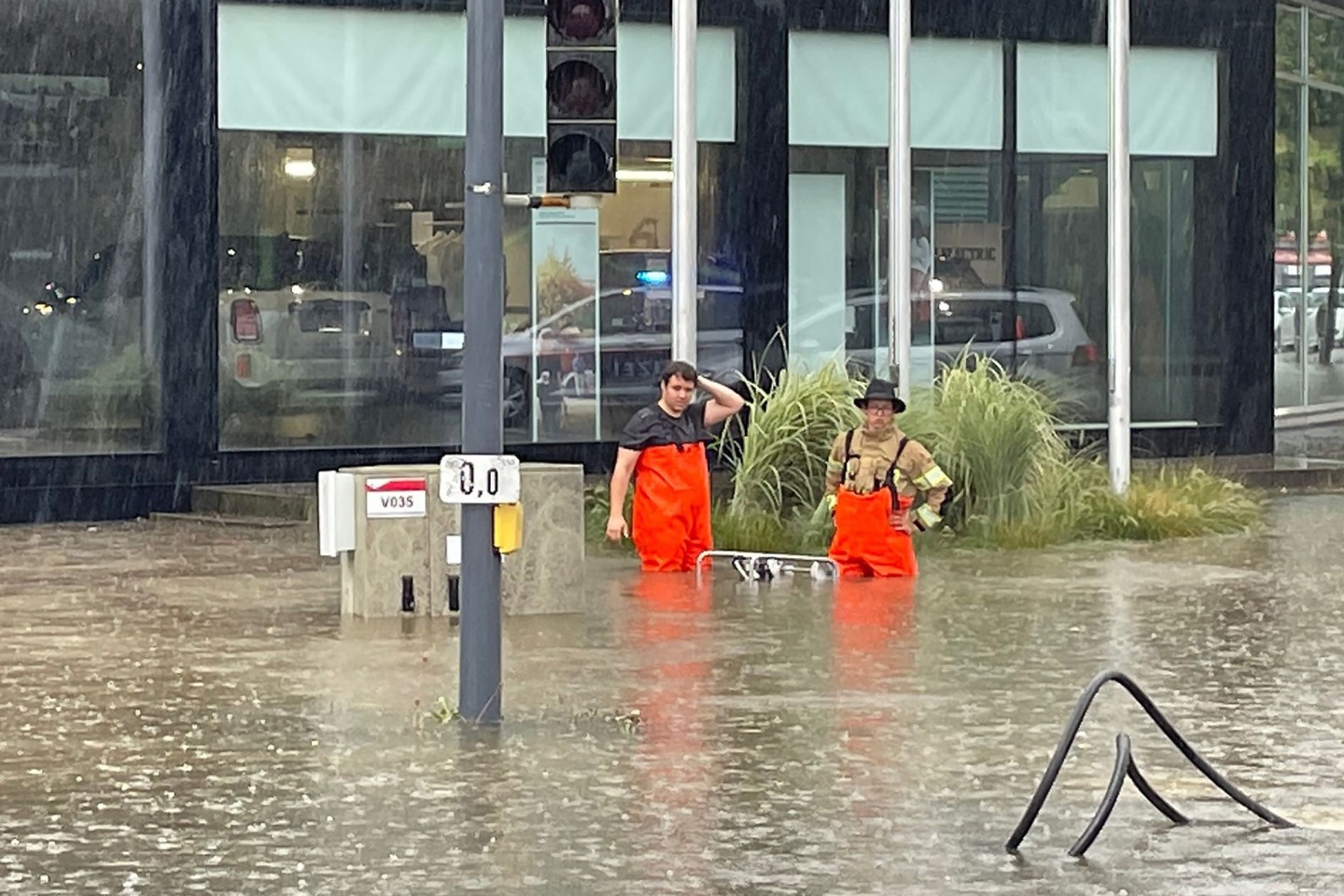 Männer auf einer überfluteten Straße in Kennelbach in Vorarlberg nach intensiven Niederschlägen.