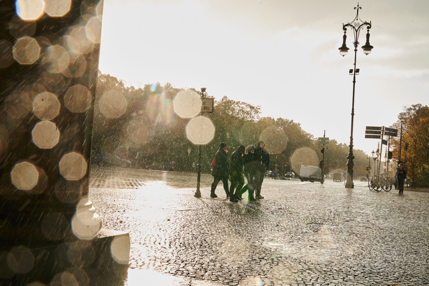 Menschen gehen in Sturm und Regen am Brandenburger Tor vorbei.