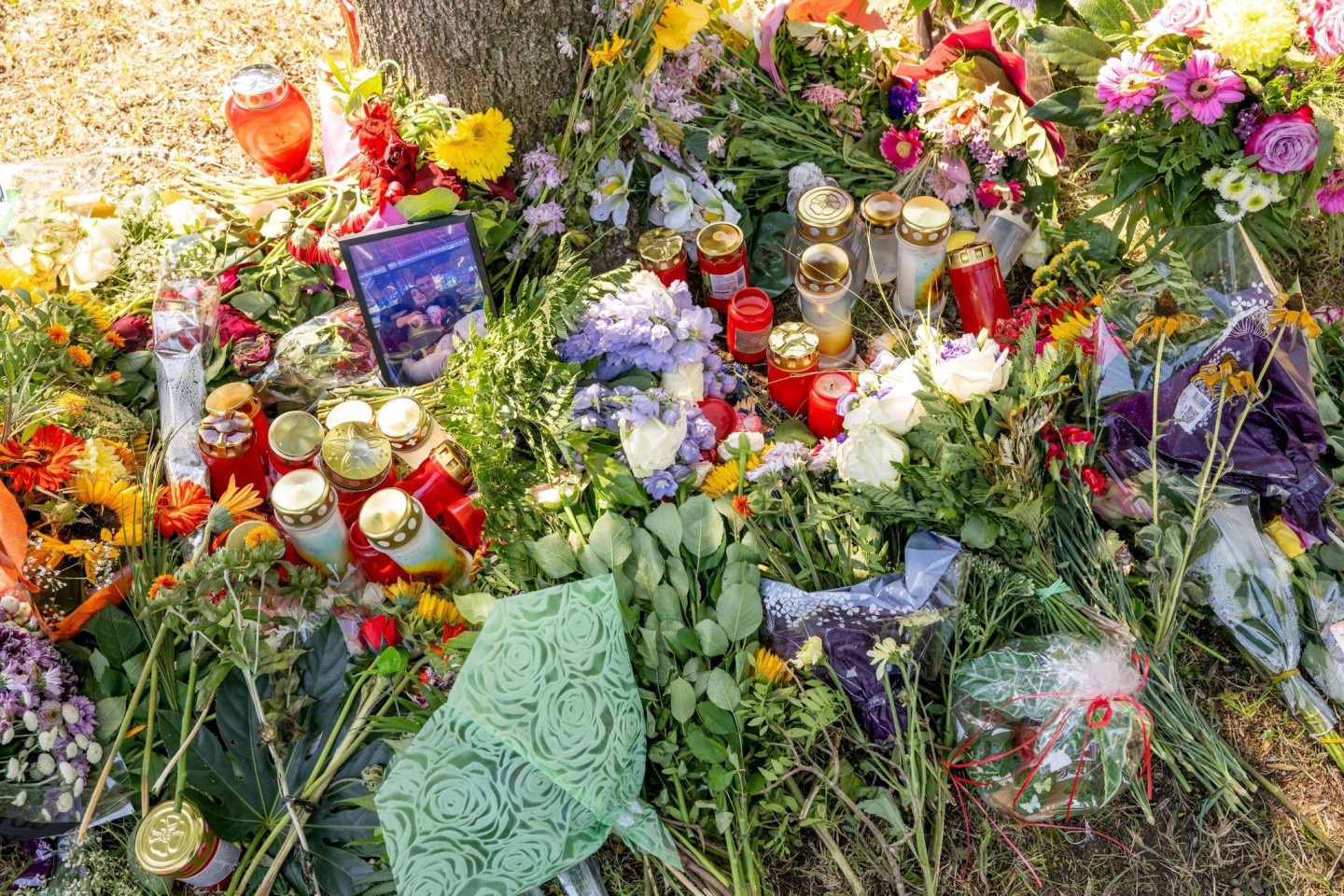 Blumen, Kerzen und Bilder liegen an einem Baum, in dessen Nähe am 17. August 2022 die tote Frau in einem Auto entdeckt wurde.