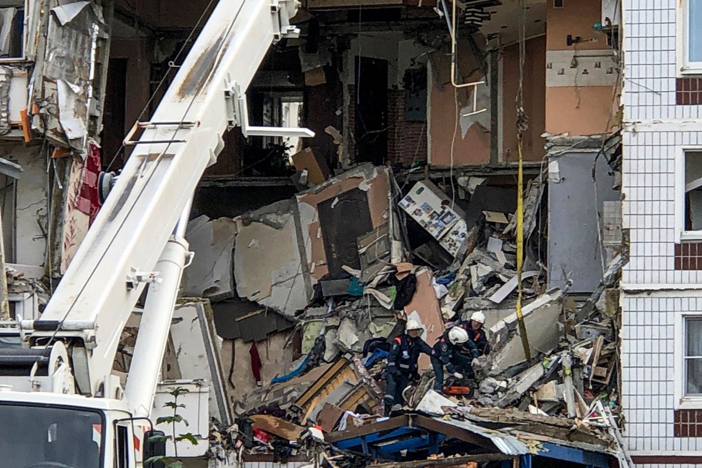 Rettungskräfte arbeiten am Ort einer Gasexplosion in einem neunstöckigen Wohnhaus, mit Toten und Verletzten.