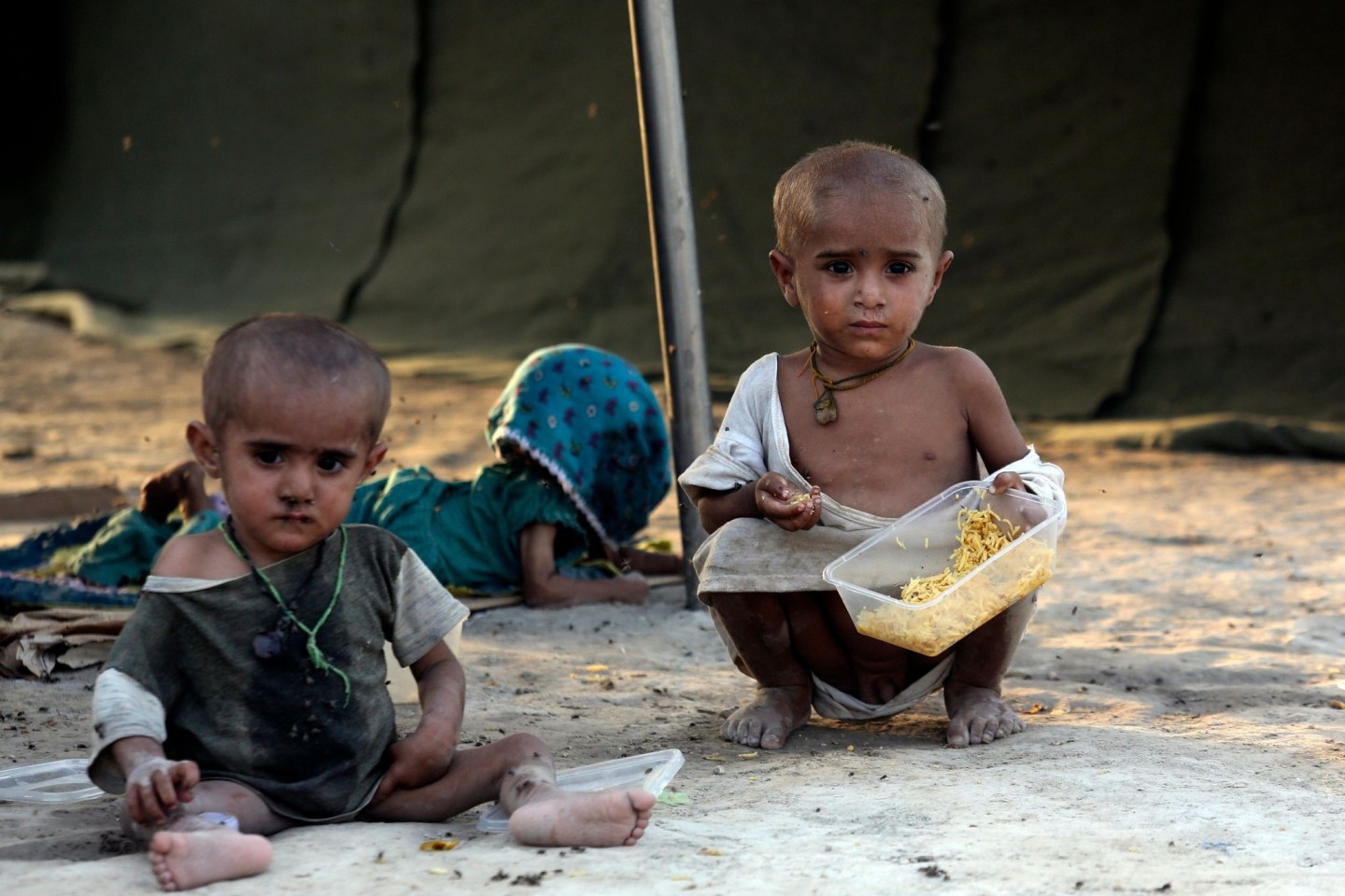 Kleinkinder, die durch die Überschwemmungen des Monsuns vertrieben wurden, essen in einem provisorischen Zeltlager für Flutopfer im pakistanischen Sukkur.