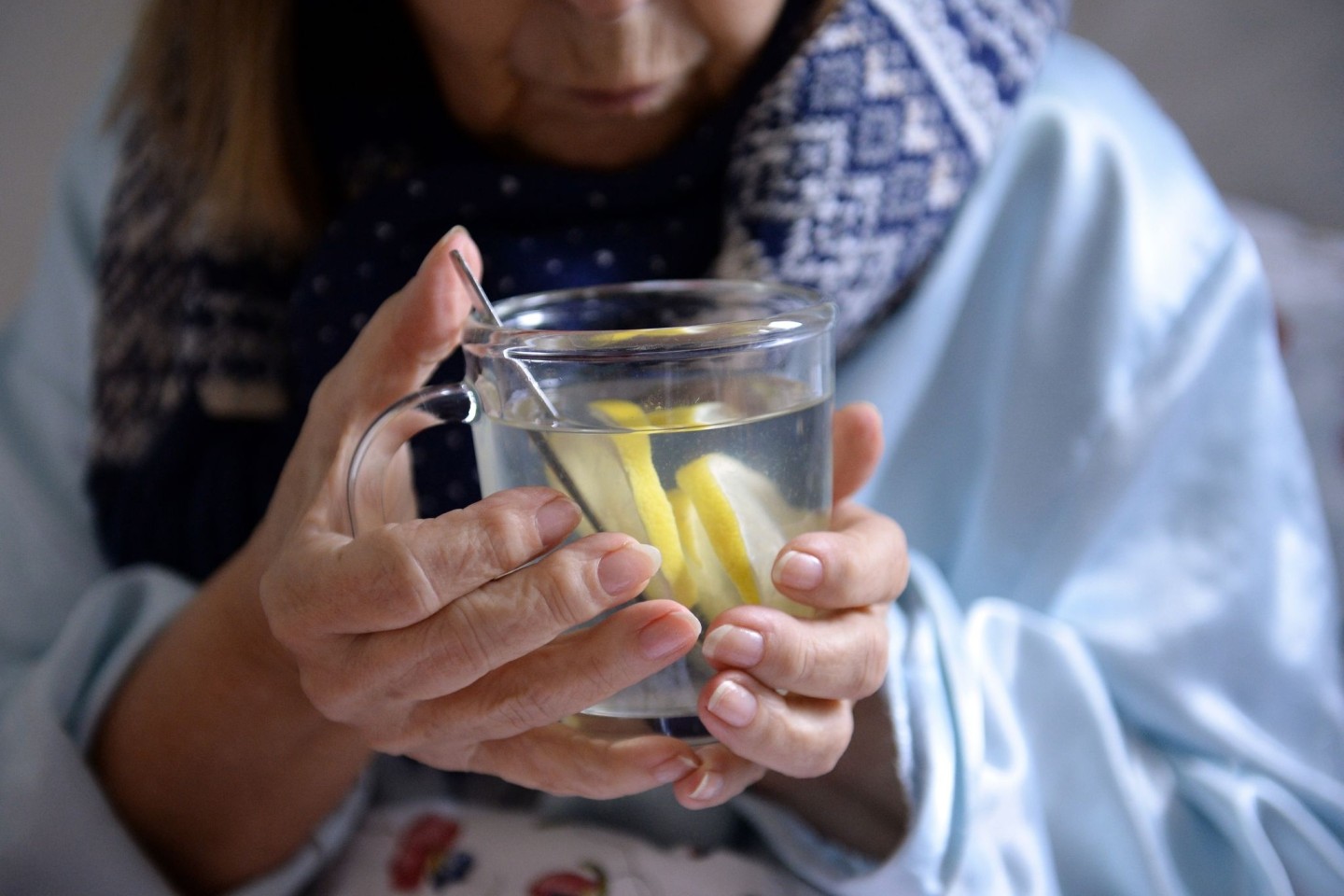 Eine Frau hält eine Tasse mit heißer Zitrone in ihren Händen.