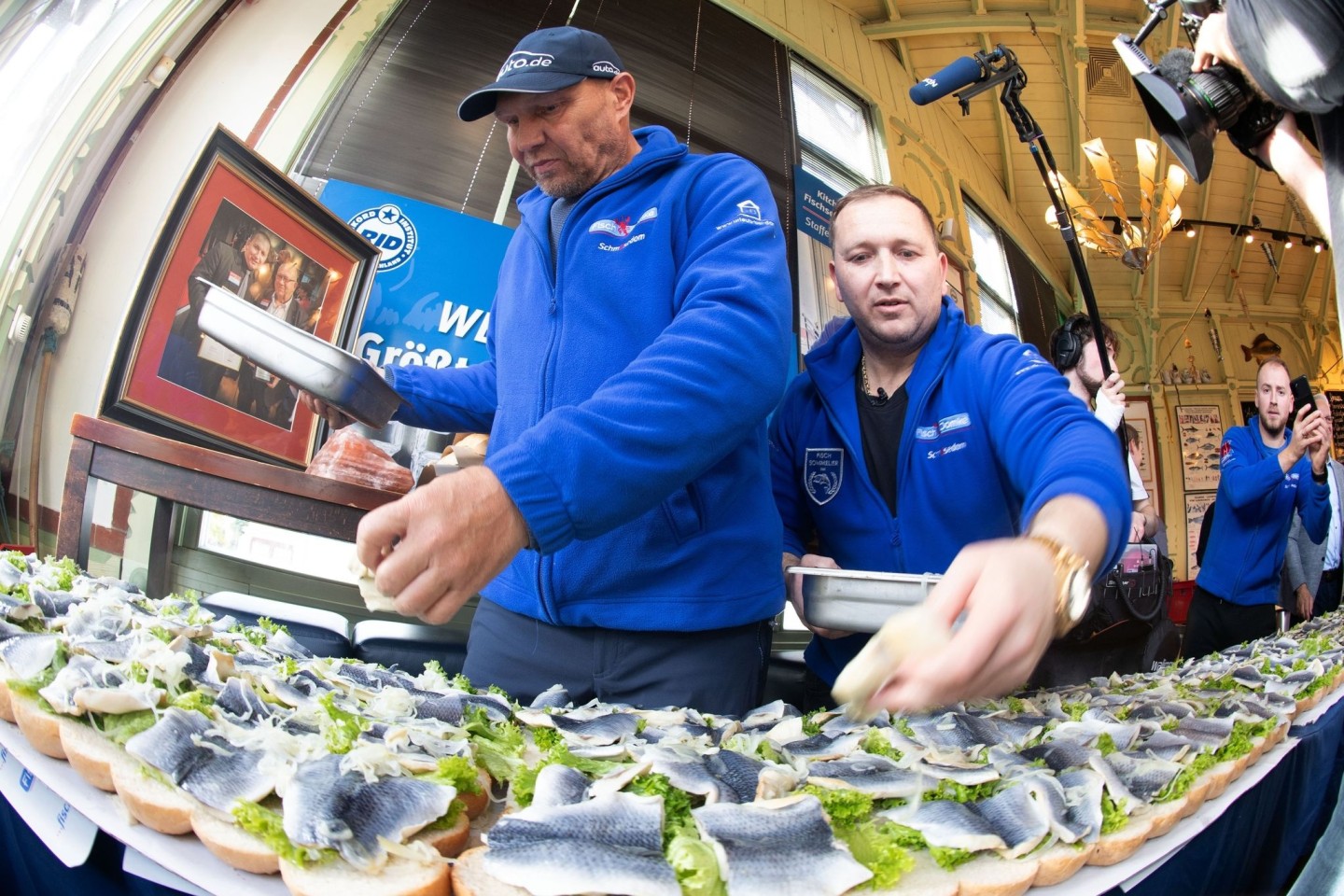 Axel Schulz, ehemalige Profiboxer (l-r), und André Domke, Fischsommelier und -händler, belegen das gigantische Fischbrötchen mit Salat, Fisch und Zwiebeln.