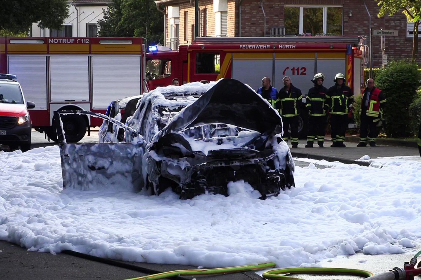 Vom Löschschaum bedeckt steht ein Auto nach einer Explosion auf der Straße im nordrhein-westfälischen Hürth.