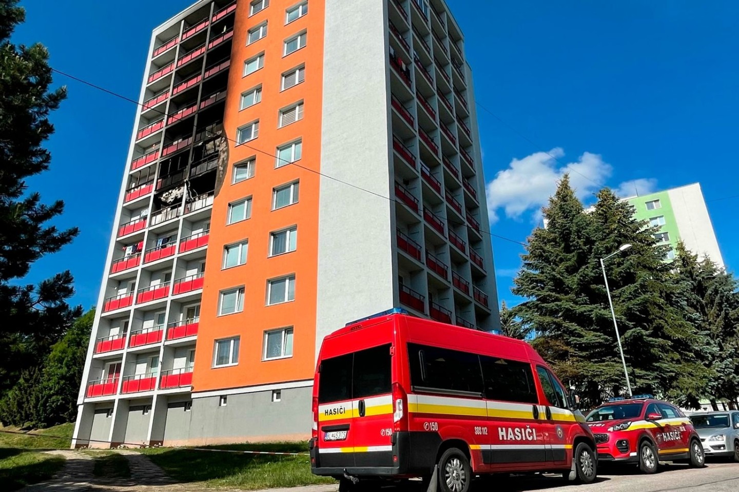 Einsatzfahrzeuge stehen vor dem Wohnhaus, in dem ein Feuer im fünften Stock ausgebrochen war.
