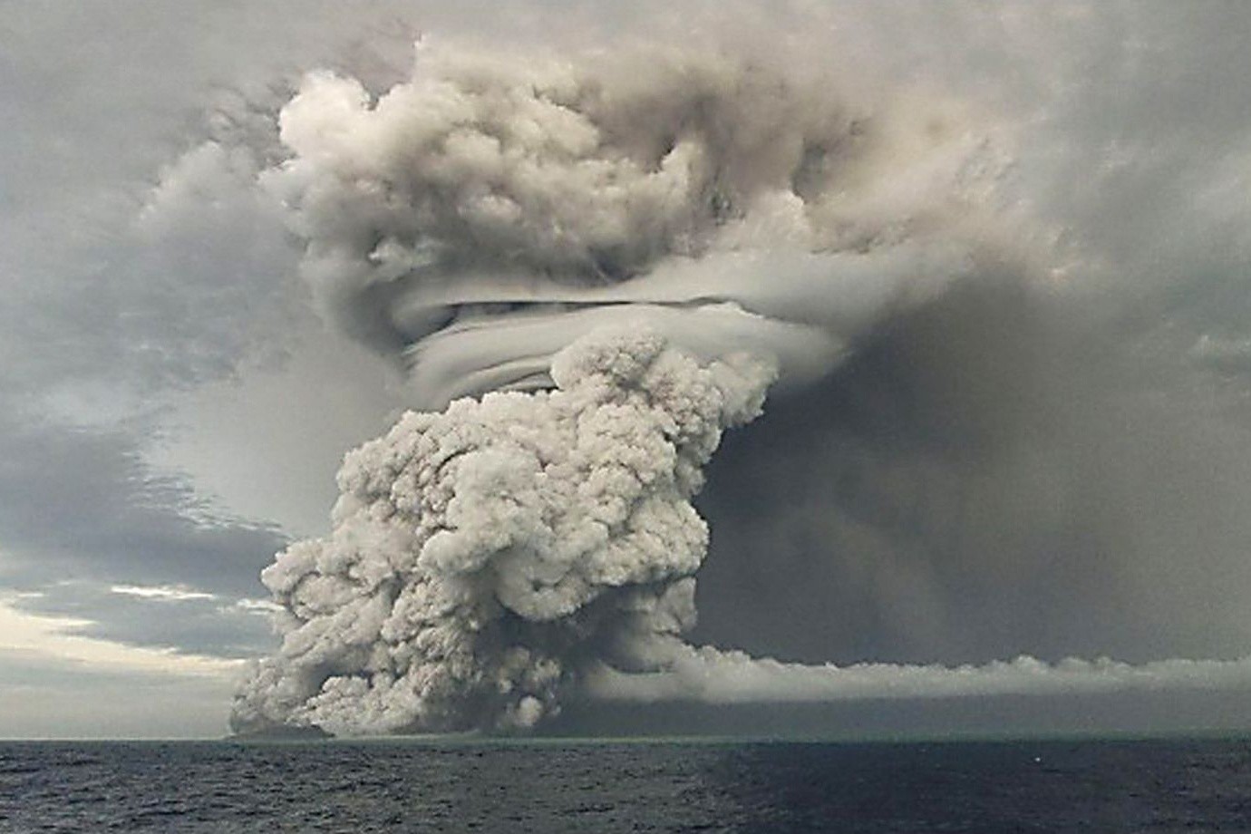Über dem Vulkan Hunga-Tonga-Hunga-Ha'apai steigt eine große Asche-, Dampf- und Gaswolke über dem Meeresspiegel auf.