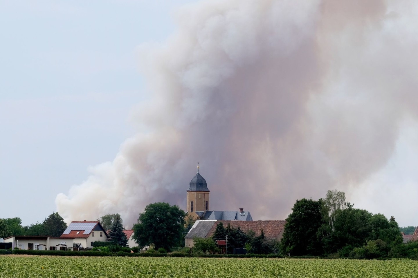 Rauch eines Waldbrandes steigt über dem Dorf Lichtensee (Landkreis Meißen) auf. Seit Donnerstag brennt es in der Gohrischheide.