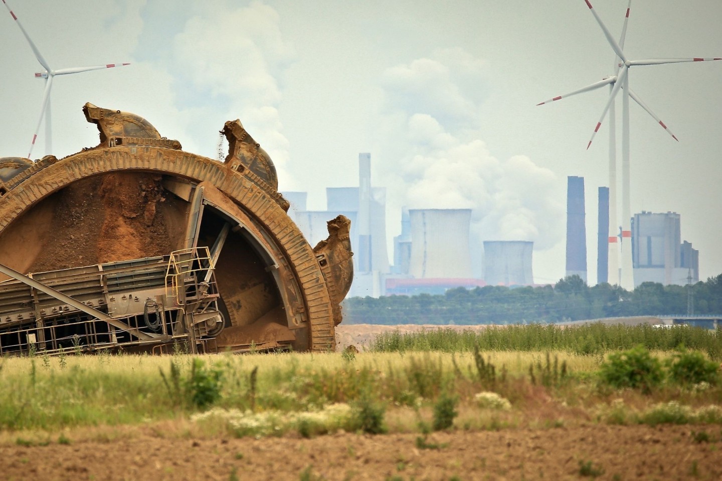 Der Schaufel eines Braunkohlebaggers baggert im Tagebau Garzeiler; im Hintergrund stehen eines der RWE-Kraftwerke und daneben Windräder. Während die Energiepreise steigen, will die COP26 i...